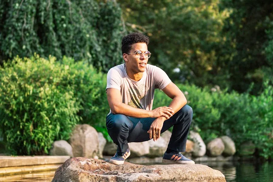 Man squatting on a rock in a peaceful sunlit pond, reflecting presence, connection, and inner abundance in nature