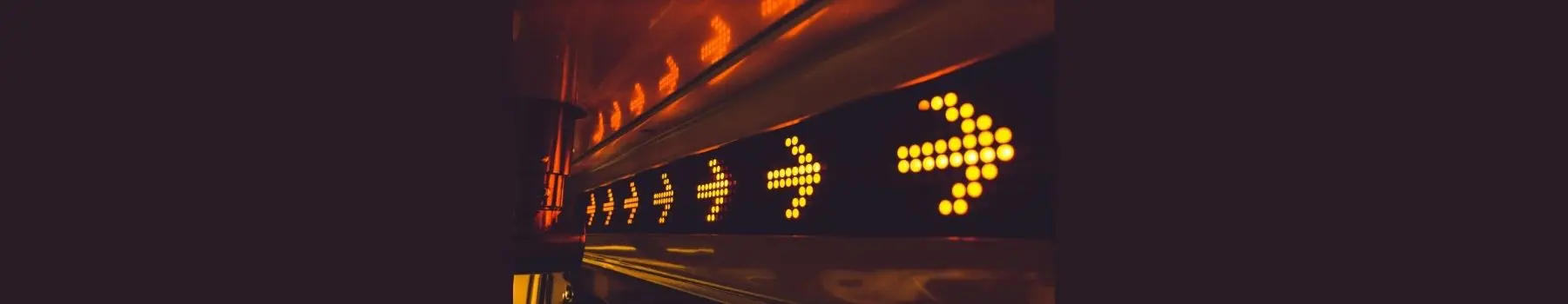 Yellow neon arrows flowing horizontally across a digital screen with red dots