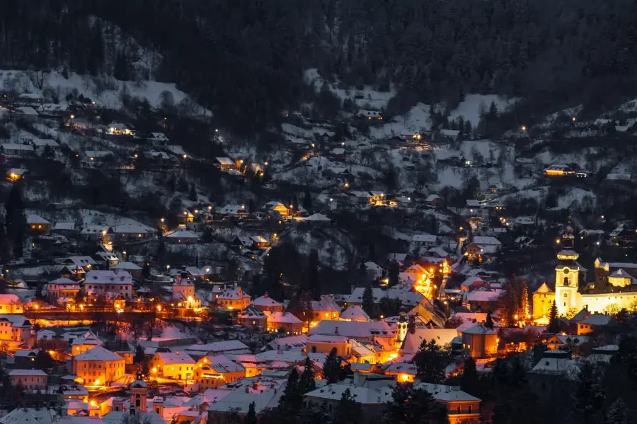 Warm lights shimmering across a snow-covered mountain village during the Winter Solstice